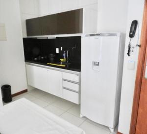 a white kitchen with a refrigerator and a sink at Apartamento excelente e espaçoso no Iloa Residence in Barra de São Miguel