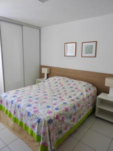 a bedroom with a bed with a colorful quilt on it at Apartamento excelente e espaçoso no Iloa Residence in Barra de São Miguel