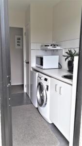 a white kitchen with a washing machine in it at Quiet location ,central to city in Hamilton