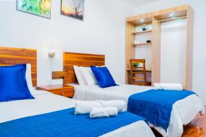 2 camas en una habitación de color azul y blanco en Hotel Boutique Platanal, en Portoviejo