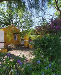 a small yellow house with flowers in the yard at POSADA EN LAS TAPIAS TRANSLASIERRAS in Las Tapias