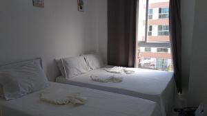 2 camas en una habitación con ventana en Muro Alto Condomínio Clube - Porto de Galinhas, en Porto de Galinhas