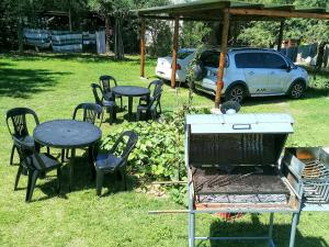 una parrilla, mesas, sillas y un coche aparcado en DEPARTAMENTOS SOSA en Mina Clavero