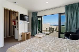 a bedroom with a king sized bed and a balcony at Studio 28 in Taupo