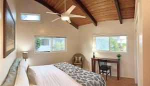 a bedroom with a bed with a ceiling fan and a desk at OceanFront Kauai - Rhythm TVNC 4288 in Kapaa