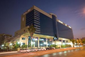 un grand bâtiment avec des voitures garées devant lui dans l'établissement Casablanca Hotel Jeddah, à Djeddah