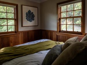 Cedar Cottage Meander في Meander: غرفة نوم بها نافذتين وسرير