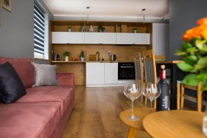a living room with a red couch and a kitchen at Apartamenty Cypryjskie in Koszalin