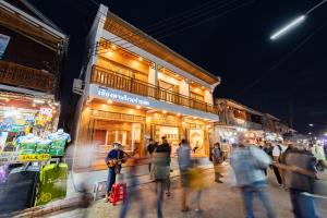 een groep mensen die 's nachts over straat lopen bij Chiangkhan River Walk Hotel in Chiang Khan