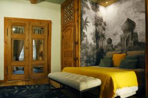 Un dormitorio con una cama amarilla y una pintura en la pared en La Demeure du Lac de Fugeres, en Le Puy en Velay
