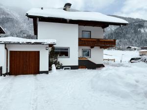 a house covered in snow with a garage at Apartment Lina in Achenkirch