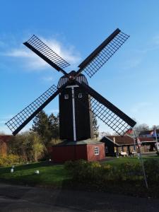 um grande moinho de vento preto num campo com um sinal de stop em Haus Valentin em Dornum