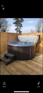 a hot tub sitting on a deck with a bench at GROOMS COTTAGE OUTSIDE HOT TUB in Beith