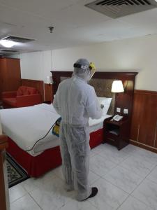 a man standing next to a bed in a room at Grand Nova Hotel in Dubai