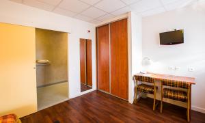 a room with a desk and a tv on a wall at Logis Hôtel Belle Vue in Les Ancizes-Comps