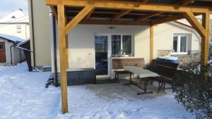 zadaszone patio z ławką i stołem na śniegu w obiekcie Apartmán Woodcock w mieście Poniklá