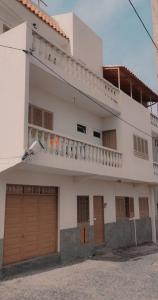 een wit gebouw met bruine deuren en een balkon bij Résidence Yô in Mindelo