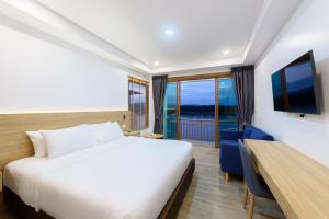 Schlafzimmer mit einem Bett, einem Schreibtisch und einem TV in der Unterkunft Chiangkhan River Walk Hotel in Chiang Khan