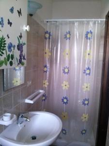a bathroom with a sink and a shower curtain with flowers at le case dei fiori in Pisciotta