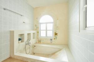 a white bathroom with a tub and a window at Talay Hotel and Villa Cha-am in Cha Am