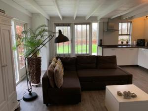 een woonkamer met een bruine bank en een keuken bij Bed & breakfast Heitse in Heythuysen