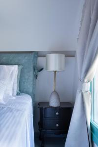 a bedroom with a bed and a table with a lamp at Santa Irina Luxury Sunny Lofts in Perivolos