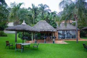 a table and chairs with umbrellas in a yard at Kosmos, Hartbeespoort in Hartbeespoort