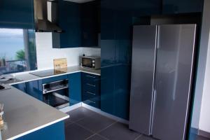 a kitchen with blue cabinets and a stainless steel refrigerator at Kosmos, Hartbeespoort in Hartbeespoort