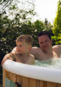 Un uomo e un bambino in una vasca idromassaggio di B&B 't Goedhof a Maaseik