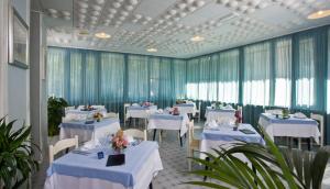 un comedor con mesas blancas y cortinas azules en Hotel San Marco, en Gabicce Mare