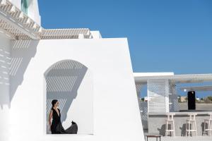 a woman sitting in the doorway of a white building at Santa Irina Luxury Sunny Lofts in Perivolos