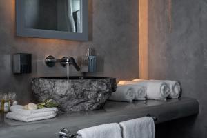a bathroom with a stone sink and towels at Santa Irina Luxury Sunny Lofts in Perivolos