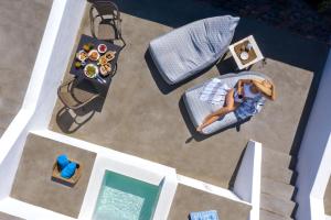 an overhead view of a woman sitting in a chair next to a pool at Santa Irina Luxury Sunny Lofts in Perivolos