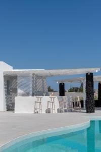 a pool with chairs and a table next to a building at Santa Irina Luxury Sunny Lofts in Perivolos