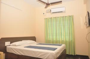 a bedroom with a bed and a green shower curtain at Hotel Aishwariyam in Tirukkadaiyūr