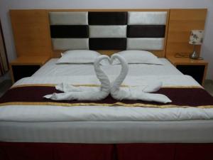 two towels in the shape of hearts are on a bed at Horizon Hotel Apartments - الأفق للشقق الفندقية in Al Khawḑ