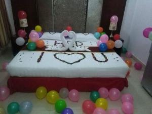 un pastel de cumpleaños con dos cisnes y globos en una cama en Horizon Hotel Apartments - الأفق للشقق الفندقية en Al Khawḑ