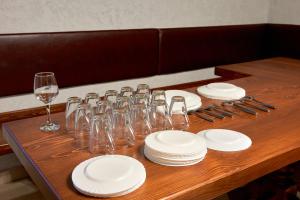a wooden table with white plates and wine glasses at Sytikland in Senatov