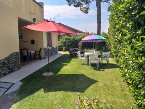 eine Terrasse mit Tischen und Sonnenschirmen auf dem Rasen in der Unterkunft Sybaris B&B in Marina di Sibari