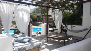 uma rede de descanso e uma cama num pátio com piscina em Hotel Mediterraneo em Chora, Ios