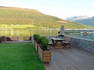 Eidsvåg的住宿－6 person holiday home in EIDSV G，湖畔木甲板,配有桌子和长凳
