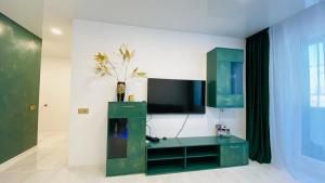 a living room with a green cabinet and a tv at Green & White Apartament in Anykščiai