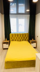 a large yellow bed in a bedroom with a window at Green & White Apartament in Anykščiai