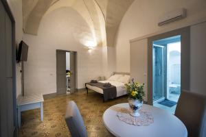 un soggiorno con letto e tavolo di Le Finestre Su Porta Carrese - Luxury Rooms & Suites a Matino