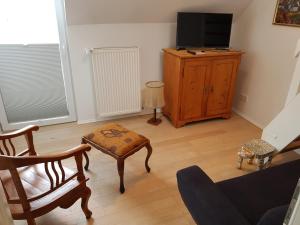 a living room with a tv and a chair and a table at Ferienhaus Am Schildberg in Sulzheim