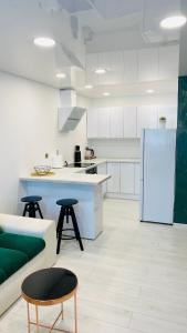 a white kitchen with a couch and a refrigerator at Green & White Apartament in Anykščiai
