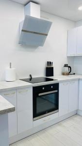 a kitchen with white cabinets and a black oven at Green & White Apartament in Anykščiai