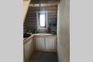 Elle comprend une petite cuisine avec un évier et une fenêtre. dans l'établissement Romantic stay at loghouse VäikeTeeMaja, à Üksnurme