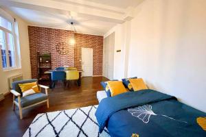 een slaapkamer met een bed en stoelen en een bakstenen muur bij Charmant T2 Hyper-centre, Netflix, Gare in Amiens