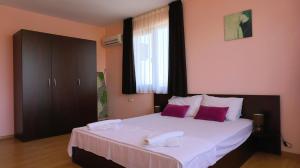 a bedroom with a large white bed with purple pillows at Вила Делфин - Villa Delfin in Bŭlgarevo +42 photos